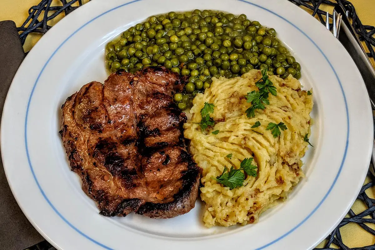 Schweinenackensteak mit Erbsen an Kartoffelstampf